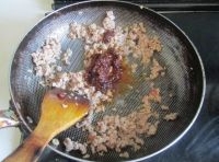 熱鍋倒油，油熱后煸炒肉末至變色，放入牛肉拌醬翻炒；