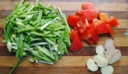 野韭菜苔洗凈切成段，紅椒、姜、蒜洗凈切成片；