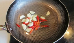 鍋里加油燒熱，把紅椒、大蒜片放進去爆香；
