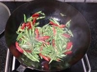 在炒鍋中加入適量的油燒熱后，倒入切片的四季豆和紅辣椒翻炒片刻；