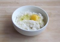 在米飯中打入一個雞蛋，攪拌均勻；