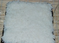 竹簾上鋪層保鮮膜，再鋪層海苔，米飯鋪在海苔上壓緊；