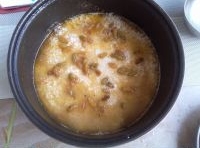 燒開的牛肉菜湯倒入電飯鍋里，大米控干水份放在菜上，撒上葡萄乾；