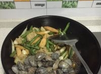 燜至花菜豆角熟透后，再將花蛤和魷魚下鍋；