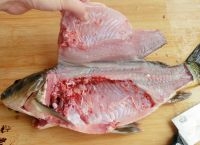 草魚的內臟清理乾淨后平置案板上，把魚頭切成兩大片；