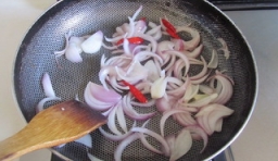 鍋內油燒熱后，加入洋蔥絲和紅辣椒爆香；