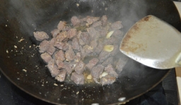 在鍋里加入適量的油，燒熱后，倒入切好的牛肉，    用大火快速翻炒牛肉；