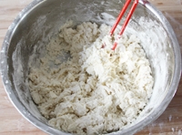 在盆中放入麵粉，分幾次倒入適量熱水，用筷子攪拌成大雪花片；