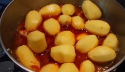加入雞塊翻炒片刻后，倒入去皮的小土豆， 在鍋中加入一些溫水；