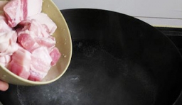 鍋中加入適量的水燒熱后，倒入塊的切五花肉；