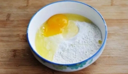 在碗里倒入乾麵粉，把雞蛋打破在裡面加點清水攪成麵糊；