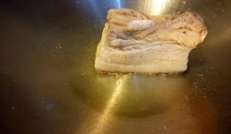 鍋燒熱后倒油，不冒煙時把豬肉放進去，豬皮上抹少許鹽入鍋煎，豬皮部位朝下慢煎大概5分鐘；