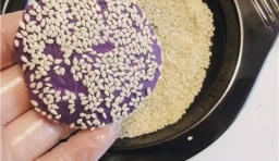 用手揉成光滑的紫薯麵糰，再摁扁，在表面蘸少許白芝麻；
