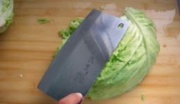 將圓白菜摘掉黃葉，用清水洗凈，一切兩半后，用刀拍鬆散；