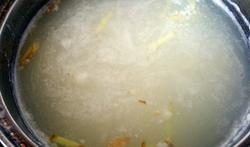 鍋里加水燒開，倒入大米和薑絲用小火慢煮，煮的過程中攪動幾次；