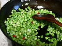 倒入切丁的豆角翻炒一會兒，再加入一點點的水，水要邊炒邊加，這樣做豆角容易熟，而且炒出的豆角是翠綠色的；