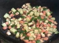 倒入切好的黃瓜丁、火腿腸丁、香菇丁翻炒一會兒，再撈出；

