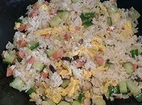 接下來倒入米飯炒至米粒透明時，再倒入炒至好的，黃瓜丁、火腿腸和香菇丁翻炒，加入適量的鹽；
