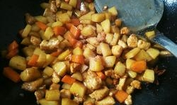 倒入切丁的土豆和胡蘿蔔丁翻炒2分鐘，加入適量的鹽和醬油翻炒均勻；