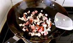 鍋中留有少許的底油，放入蒜片，炒出香味后，加入香腸丁、海鮮菇丁和木耳略炒片刻；