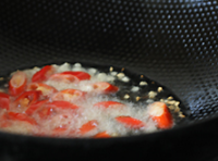燒熱炒鍋，加入適量的，待油溫熱后，下入切段朝天椒和蒜粒炒出香味；
