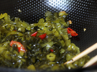 最後倒入切絲的酸菜炒至，調入少許的米酒、鹽和少許的味精翻炒均勻即可。